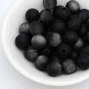 Gros plan détail de perles œil de chat mates noires dans un bol blanc pour bijoux DIY.