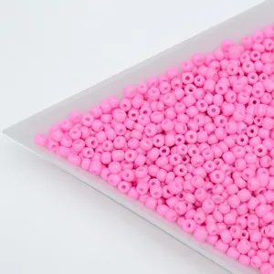 Close-up detail shot of pink solid barrel seed beads for DIY handmade jewelry bracelets.
