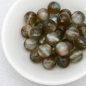 Close-up detail of dreamy jelly cat eye round beads in white bowl for handmade DIY jewelry.