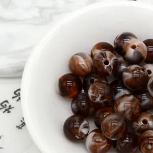 Close-up detail of retro brown marbled acrylic loose beads in a white bowl for DIY.