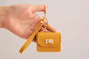 Mini monedero de piel PU amarilla con cierre metálico y correa para la muñeca, detalle.