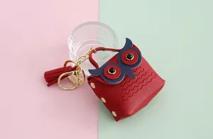 Primer plano del mini monedero de piel sintética con diseño de búho rojo y borla elegante.