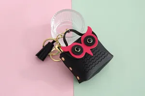 Detalle en primer plano del mini llavero monedero de cuero PU con búho y borla dorada.