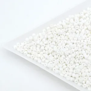 Close-up detail of white glass seed beads, small loose barrel beads for DIY handmade jewelry.