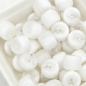 Close-up detail of white resin barrel beads, smooth glossy surface for jewelry crafting.