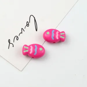 Close-up of pink acrylic fish shaped beads with colorful details for DIY jewelry crafting.