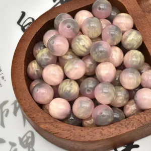 Close-up detail of colorful resin beads with pink grey and gold swirled patterns for DIY crafts.