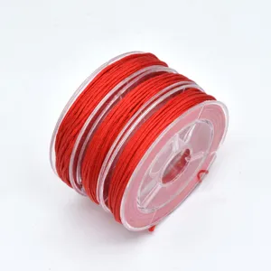 Close-up detail of bright red jade cord wound on a clear plastic spool for DIY jewelry.