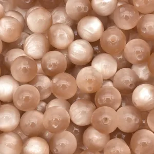 Close-up detail of champagne resin cat-eye beads, showing chatoyancy luster and drill holes.
