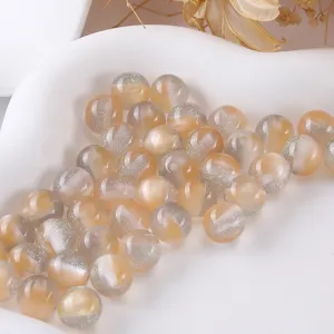 Detailed close-up of amber resin glitter beads showing shimmering texture for craft use.
