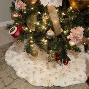White plush Christmas tree skirt with gold sequin snowflakes for holiday party decor.