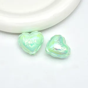 Close-up of light green iridescent acrylic balloon heart beads, perfect for diy jewelry.