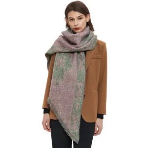 Detail view of a thick boucle yarn diagonal winter scarf with abstract pattern worn by model.