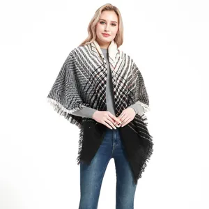 Close-up of black and white plaid fringed shawl cape, showcasing cozy winter texture.