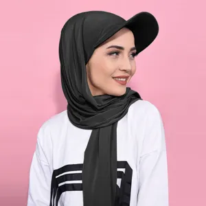 Gros plan d'un hijab sportif noir avec visière, porté par un mannequin sur fond rose.