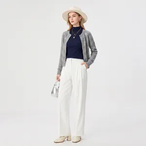 Close-up detail of grey knit cardigan layered with dark turtleneck sweater and white trousers.