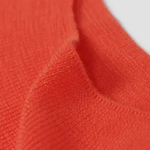 Orange wool knit sweater fabric detail closeup, soft texture, comfortable apparel material