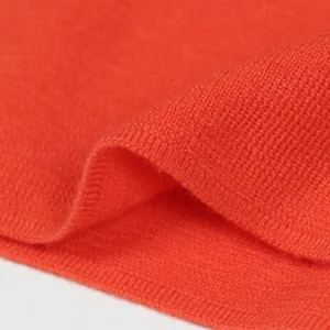 Close up view of orange knitwear fabric, soft texture detail showing wool material.