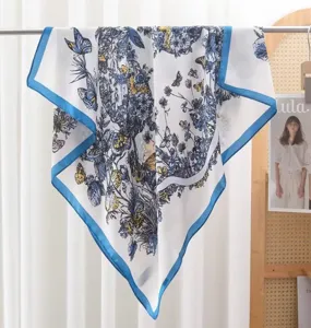 Chic floral and butterfly print square scarf with blue border, lightweight silk-feel fabric.