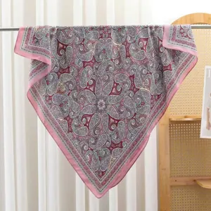 Detail view of a vintage paisley print square scarf with classic pink and red motifs.