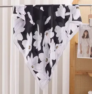 Detail view of a black and white floral satin square scarf hanging elegantly indoors.