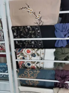 Detailed view of ethnic embroidered scarves and cashmere-feel shawls neatly arranged on display rack.