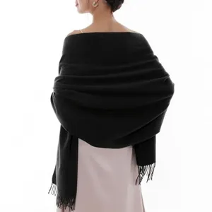 Detailed view of the black solid-color fringed scarf worn on back, soft cashmere-feel fabric.