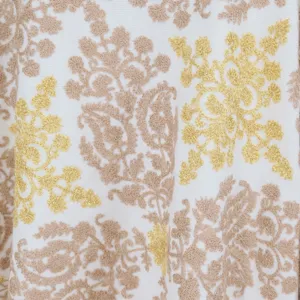 Close-up detail shot of elegant gold and brown embroidery pattern on soft fabric background.