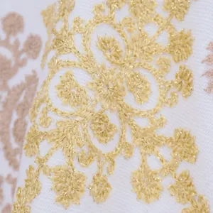 Cashmere scarf detail shot featuring elegant gold thread floral embroidery on white fabric.