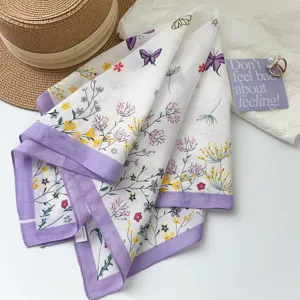 Foulard carré en coton à motif de fleurs et papillons, bordure violette élégante.