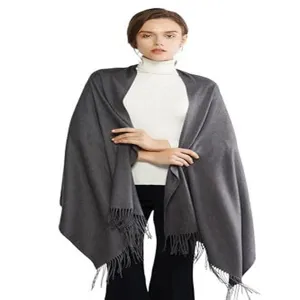 Close-up detail of soft solid color dark grey winter tassel shawl fabric and fringes.