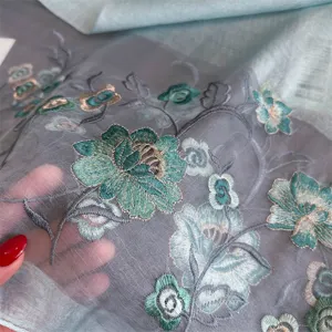 Detailed view of sheer silk scarf with exquisite green and gold floral embroidery patterns.
