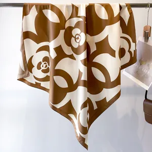 Detail view of brown and white camellia patterned silk square scarf hanging on display.