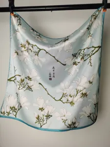 Detailed view of light blue silk square scarf with magnolia print and classical art.