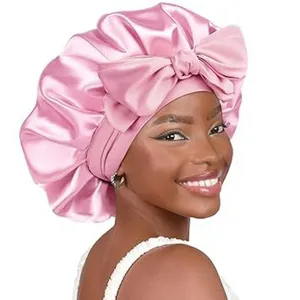 Detail view of pink satin hair sleep bonnet with large bow, soft double layer fabric for care.