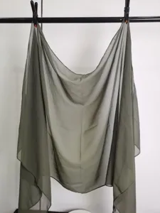 Close-up detail of a lightweight olive green chiffon scarf hanging on display. Soft fabric texture.
