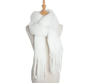 Close-up detail of white fluffy winter scarf with tassels. Soft knit warm winter accessory.