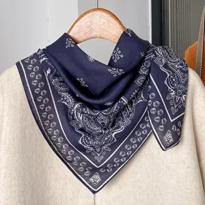 Detailed shot of a dark blue paisley cotton linen square scarf hanging on a wooden hanger.