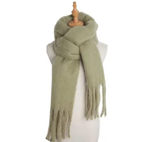Close-up detail of soft sage green fuzzy winter scarf texture, showcasing warm knit loops and fringe.
