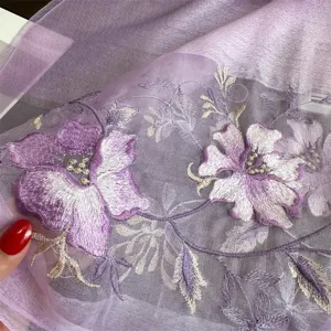 Closeup of purple silk wool embroidered shawl detail, showcasing delicate floral embroidery texture.
