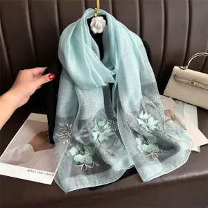 Detailed view of the light blue silk wool scarf featuring exquisite floral embroidery craftsmanship.