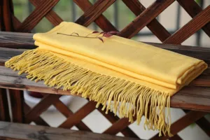 Detalle de bufanda amarilla con flecos, elegante textura de tela para el uso diario.
