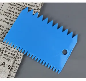 Dettaglio ravvicinato di raschietto per torta in plastica blu con bordi dentati e foro.