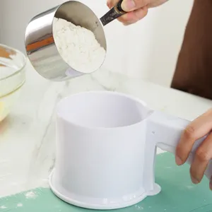 Detailed view of handheld flour sifter in use, showing sifting mechanism and baking setup.