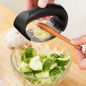 Manual stainless steel garlic press kitchen tool with curved handle for easy garlic mincing.