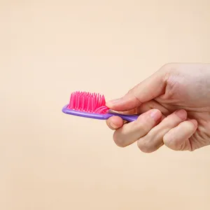 Spazzola per capelli mini a griglia con setole rosa per uno styling portatile e da viaggio.
