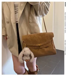 Vintage brown faux suede shoulder bag with metal lock and cute bunny charm for stylish women daily.