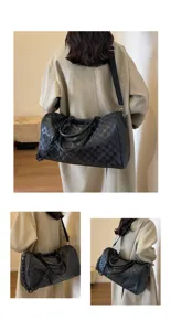 Detailansicht der schwarzen karierten Reisetasche mit großem Volumen und Schultergurt.