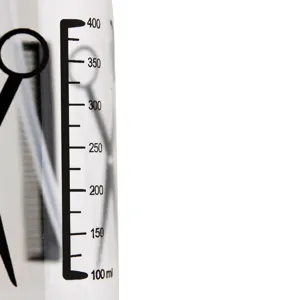 Flacone spray trasparente per parrucchieri in plastica con scala graduata e forbici.
