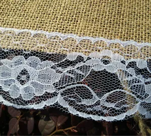 Dettaglio in juta rustica e pizzo bianco, perfetto per decorazioni di feste nuziali.